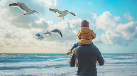 A father carrying his son on his shoulders while walking along the beach, with seagulls flying overhead and the ocean in the background.の素材