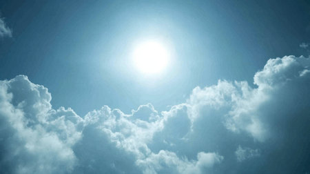 A bright sun shines over soft white clouds in a clear blue sky, creating a serene and tranquil atmosphere perfect for nature-themed projects.の素材