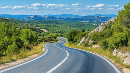A scenic winding road stretches through lush green landscapes under a bright blue sky. Enjoy the beauty of nature and the tranquility of travel.の素材