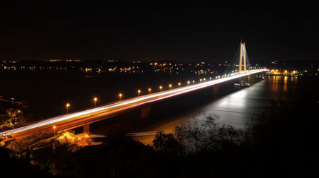 A stunning nighttime view of a modern bridge illuminated by traffic lights, reflecting on the water, showcasing the beauty of urban architecture and engineering.の素材