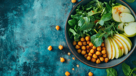 A vibrant salad bowl featuring mixed greens, sliced apples, and roasted chickpeas, perfectly arranged on a rustic blue background, ideal for healthy meal inspirations.の素材