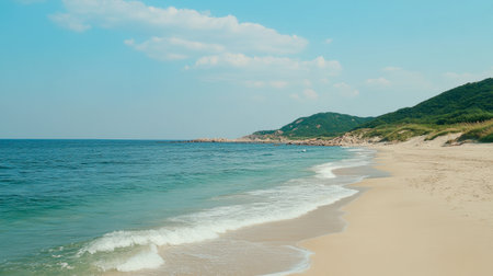 Enjoy a tranquil beach landscape showcasing gentle waves, soft sand, and lush green hills under a clear blue sky, perfect for relaxation and outdoor adventures.の素材