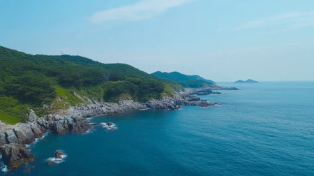 Captivating aerial view showcasing a rugged coastline with clear blue water and vibrant green hills, perfect for illustrating nature's beauty and tranquility.の素材