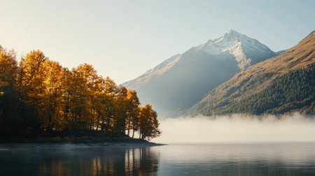 Captivating autumn scene featuring a majestic mountain rising above a tranquil lake, surrounded by vibrant yellow trees and soft morning mist, embodying peace and beauty in nature.の素材