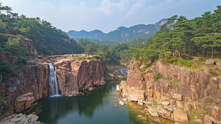 A captivating view of a waterfall flowing into a pristine river, framed by lush greenery and dramatic mountain scenery, ideal for nature and travel enthusiasts.の素材