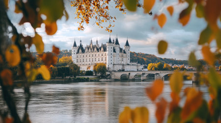 A stunning view of a majestic castle surrounded by colorful autumn foliage, reflecting in a calm river under a dramatic sky, offering a serene and picturesque landscape.の素材