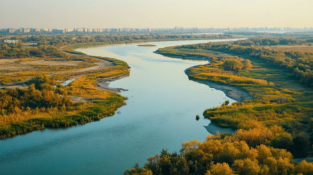 Explore a breathtaking landscape showcasing a meandering river nestled between vibrant greenery and distant city structures, evoking tranquility and natural beauty.の素材