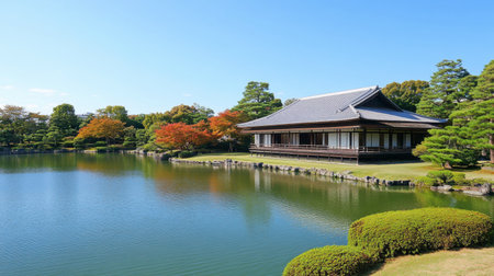 A serene Japanese garden showcasing traditional architecture by a tranquil pond, surrounded by vibrant autumn foliage under a clear blue sky. Ideal for relaxation and meditation.の素材