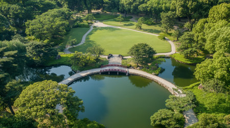 A stunning aerial view captures the beauty of a lush green park, featuring tranquil water bodies and a charming bridge, inviting visitors to relax and explore.の素材