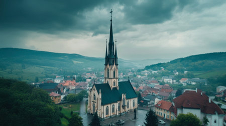 A breathtaking view of a historic church with a tall spire surrounded by a serene village landscape under dramatic cloudy skies, capturing the essence of peaceful rural life.の素材