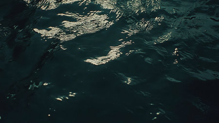 A tranquil view of a dark water surface with gentle ripples and reflections. The scene captures a sense of calmness and beauty in nature, ideal for various design projects.の素材