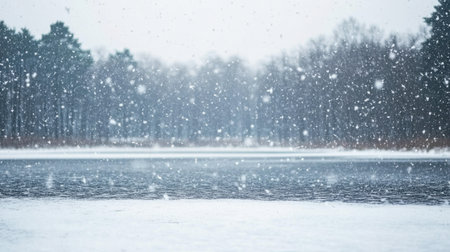 A serene winter scene showcasing gentle snowfall over a calm lake, surrounded by trees. The tranquil atmosphere captures the beauty of nature in winter.の素材