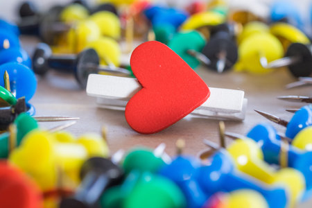 Heart of paper clip about love relationship with many pins for background.