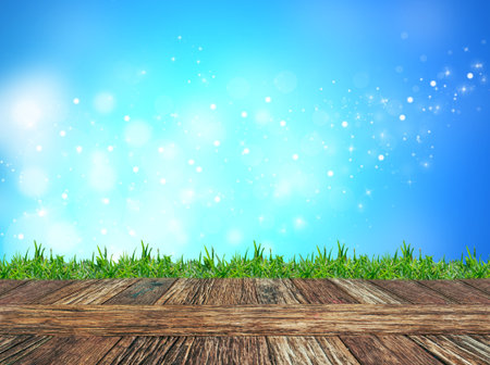 Empty wooden deck table and grass with blue glitter sparkle defocused rays lights bokeh abstract background. Product display templateの写真素材