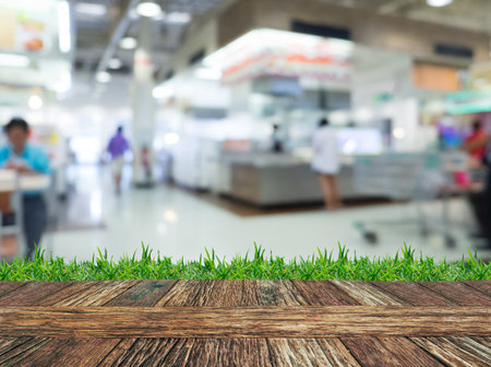 Empty wooden table and grass with blurred supermarket background. Product display template.の写真素材