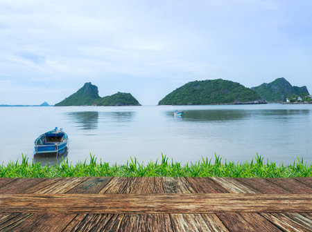 Empty wooden table and grass with sea and mountain natural background. Product display template.の写真素材