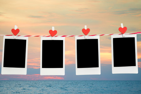 4 Blank instant photo and red clip paper heart hanging on the clothesline with wood background.Designer concept.の写真素材