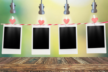 4 Blank instant photo and red clip paper heart hanging on the clothesline with black background.Designer concept.の写真素材