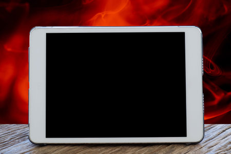Tablet Computer on table with blurred red smoke abstract dark   background.