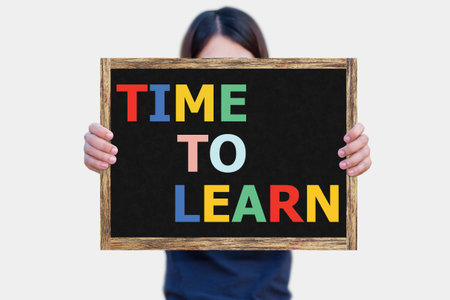 TIME TO LEARN message on the blackboard wooden frame on hand woman with white background.の写真素材