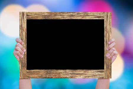 Hand woman holding blackboard wooden frame with colorful glitter sparkle ray abstract background....