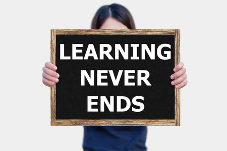 LEARNING NEVER ENDS message on the blackboard wooden frame on hand woman with white background.の写真素材
