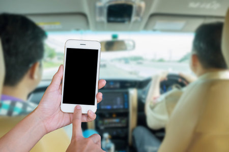 Hands woman are holding touch screen smart phone,tablet on blurred man driving car background.の写真素材