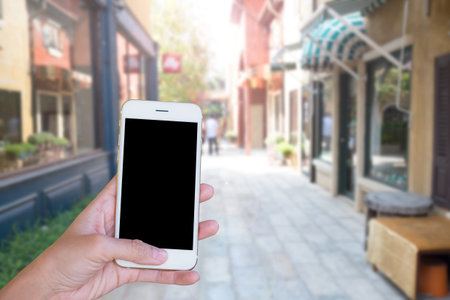 Hands woman are holding touch screen smart phone,tablet on blurred old building background.の写真素材