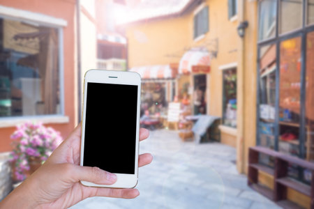 Hands woman are holding touch screen smart phone,tablet on blurred street markets old building style background.の写真素材