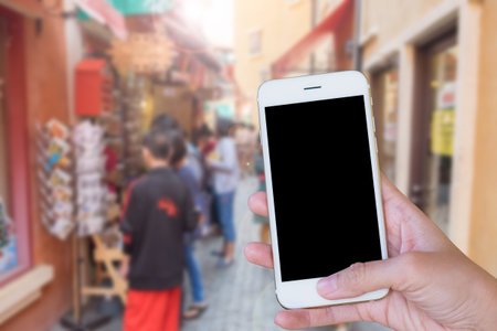 Hands woman are holding touch screen smart phone,tablet on blurred people shopping on street markets old building style background.の写真素材