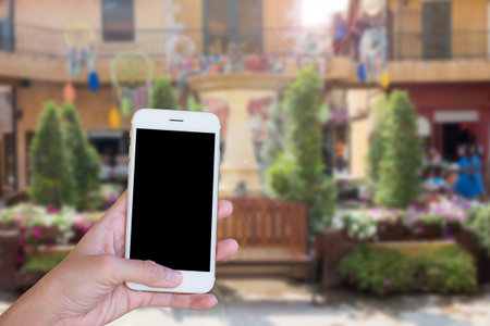 Hands woman are holding touch screen smart phone,tablet on blurred park garden nature background.の写真素材