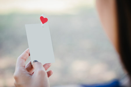 Woman looking love photo on hand and nostalgia lovers. Blank photo and red clip paper heart. relationship concept.の写真素材
