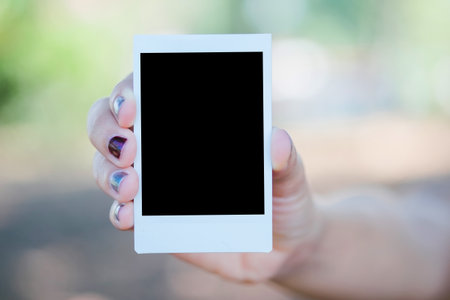 Close up hand woman hold  photo instant on hand with nature background. Blank instant photo. relationship concept.の写真素材
