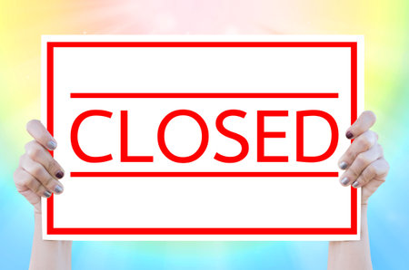 Hand woman holding whiteboard with CLOSED word on colorful background.Business concept.の写真素材