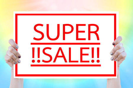 Hand woman holding whiteboard with SUPER SALE word on colorful background.Business concept.