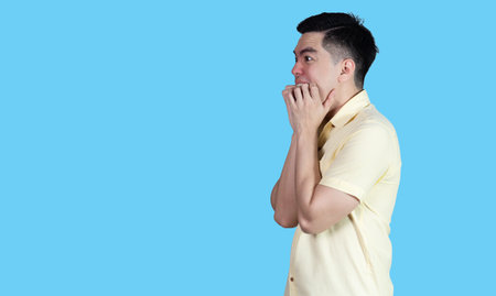 Portrait handsome young asian man wearing a yellow shirt stressed and anxiety sign isolated on blue background in studio.Asian man people.business concept.の写真素材