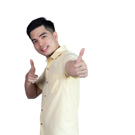 Portrait handsome young asian man wearing a yellow shirt showing thumbs up sign isolated on white background. Asian man people. business success concept.の写真素材
