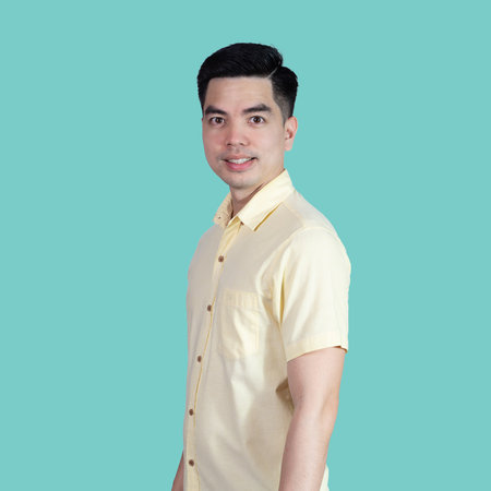 Portrait handsome young asian man wearing a yellow shirt smile  sign isolated on blue background. Asian man people. business success concept.の写真素材