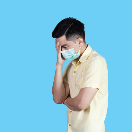Stressful  portrait handsome young asian 
man wearing yellow shirt and maskの写真素材