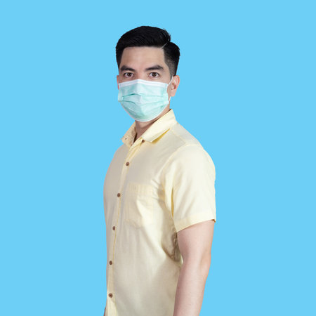 portrait handsome young asian 
man wearing yellow shirt and maskの写真素材