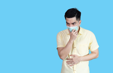 portrait handsome young asian 
man wearing yellow shirt and sneezingの写真素材