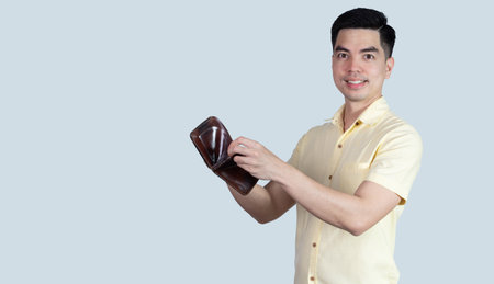 COVID-19 Coronavirus close up handsome young asian man wearing yellow shirt holding tablet and mask protection from covid 19 isolated on white background in studio. Asian man people.の写真素材