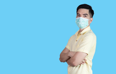 COVID-19 Coronavirus close up handsome young asian man wearing yellow shirt holding tablet and mask protection from covid 19 isolated on white background in studio. Asian man people.の写真素材