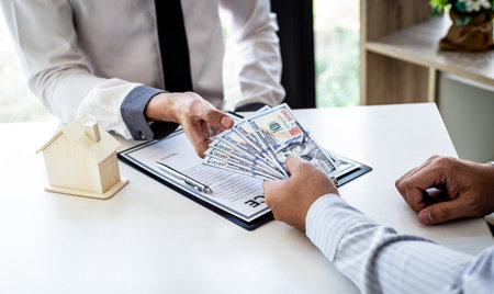 Real estate and insurance agents gave the house to customers who paid with dollar bills, Financial audit, accounting for business people concepts.の写真素材