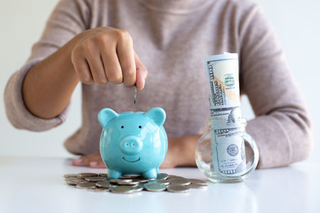 The businessman's hand holds the money in the piggy bank for saving money for future use, saving money for finance accounting concept.の写真素材