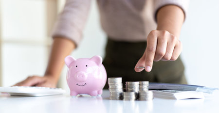 The businessman's hand holds the money in the piggy bank for saving money for future use, saving...