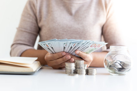 The hands of business women Hold a banknote, a dollar count money Prepare to record income and daily...