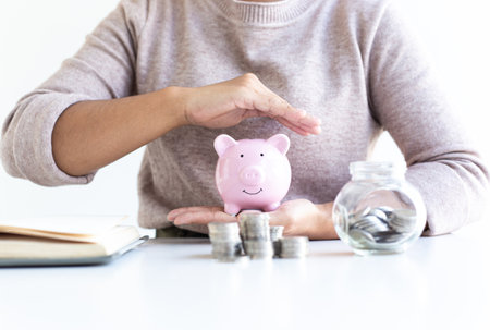 The hands of businessmen are protecting money savings in the piggy bank, increasing tax efficiency and reducing investments, Save money concept.の写真素材