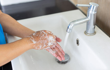Man is washing his hands in a sink sanitizing the colona virus for sanitation and reducing the...