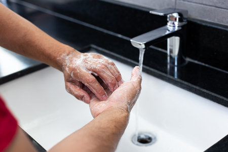 Man is washing his hands in a sink sanitizing the colona virus for sanitation and reducing the...